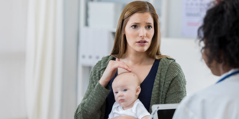 A concerned mother talking to pediatric dermatologist about her babies skin condition