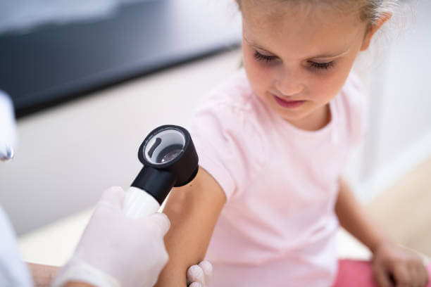 Medical Doctor Examining Child Doctor Using Dermatology Device