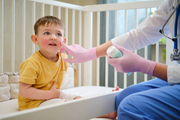 The pediatric dermatologist is applying a moisturizing lotion to the child's face before bedtime. Kid aged about two years (one year eleven months)